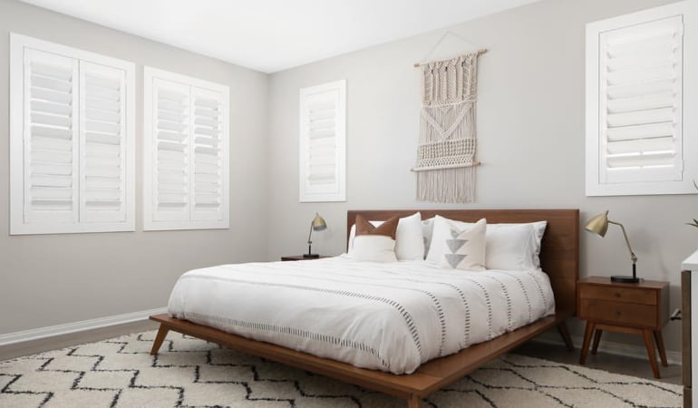Open shutter louvers will help any New York room feel larger. Plantation shutters in a model home bedroom.